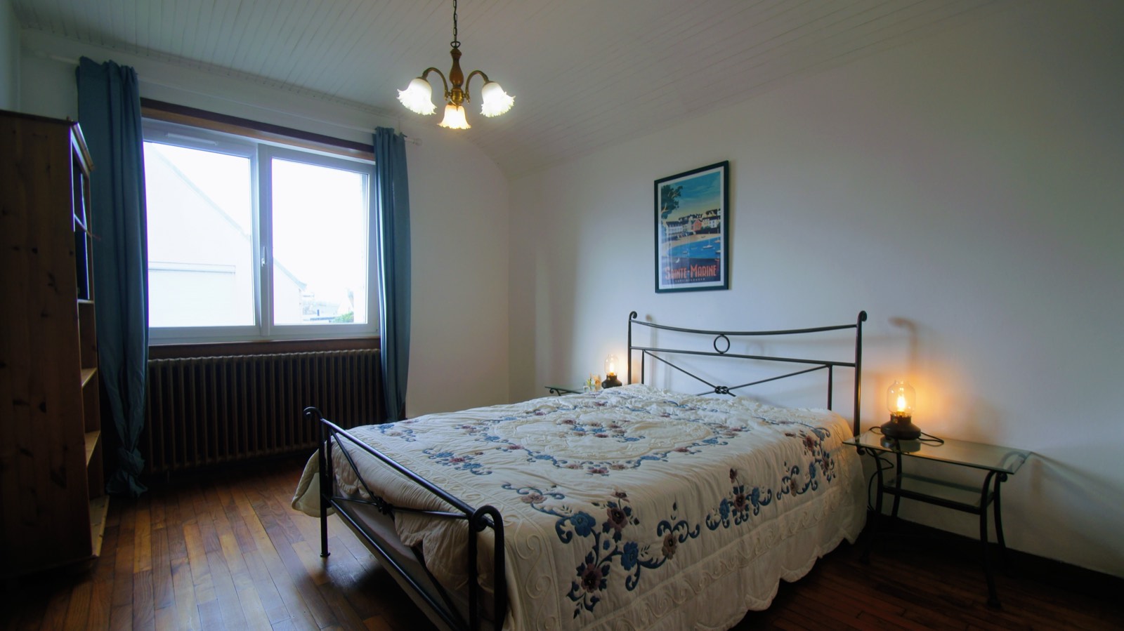 Chambre avec lit en fer forgé et couvre-lit fleuri